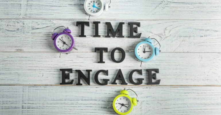 Clocks and phrase TIME TO ENGAGE on wooden background